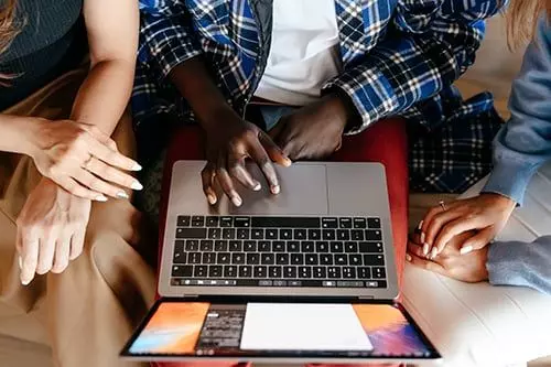 3 people gathered around a laptop from above